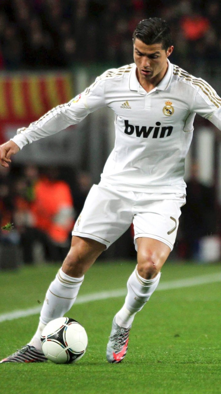 Phone wallpaper featuring Cristiano Ronaldo in Real Madrid C.F. kit controlling a soccer ball during a match, capturing dynamic sports action for iPhone and Android screens.