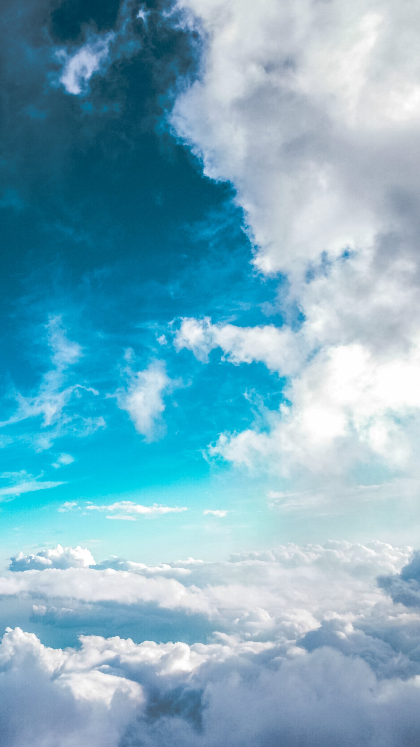 Aerial view of nature: deep blue sky and layered white clouds filling a vertical phone wallpaper.