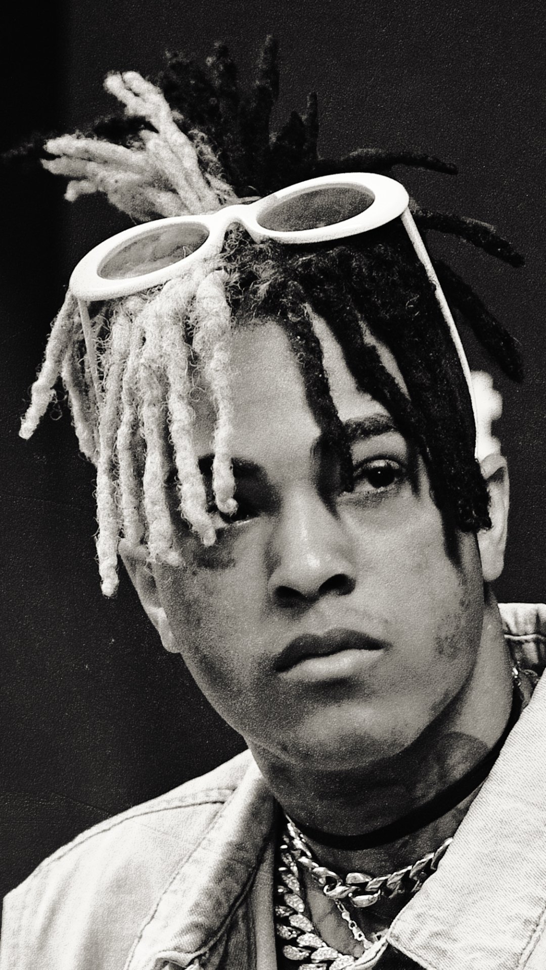 Black and white portrait of XXXTentacion with distinctive half-black, half-white dreadlocks and white sunglasses on his head, designed as a phone wallpaper for iPhones and Androids.