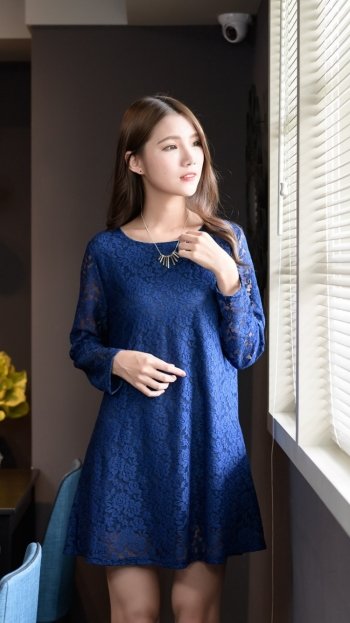 Brunette woman model in a blue lace dress gazing out a window, soft natural light — phone wallpaper.