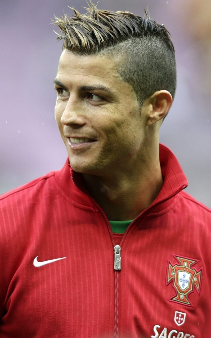 Close-up portrait of Cristiano Ronaldo in Portugal's red sports jacket, designed as a vibrant phone wallpaper for iPhones and Android devices.