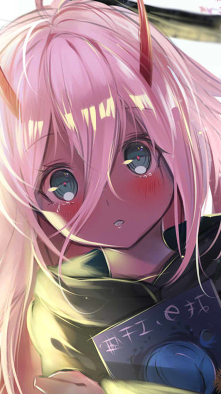 Close-up phone wallpaper of Zero Two (Darling in the FranXX): pink-haired, small red horns, flushed cheeks and large blue eyes, clutching a book.