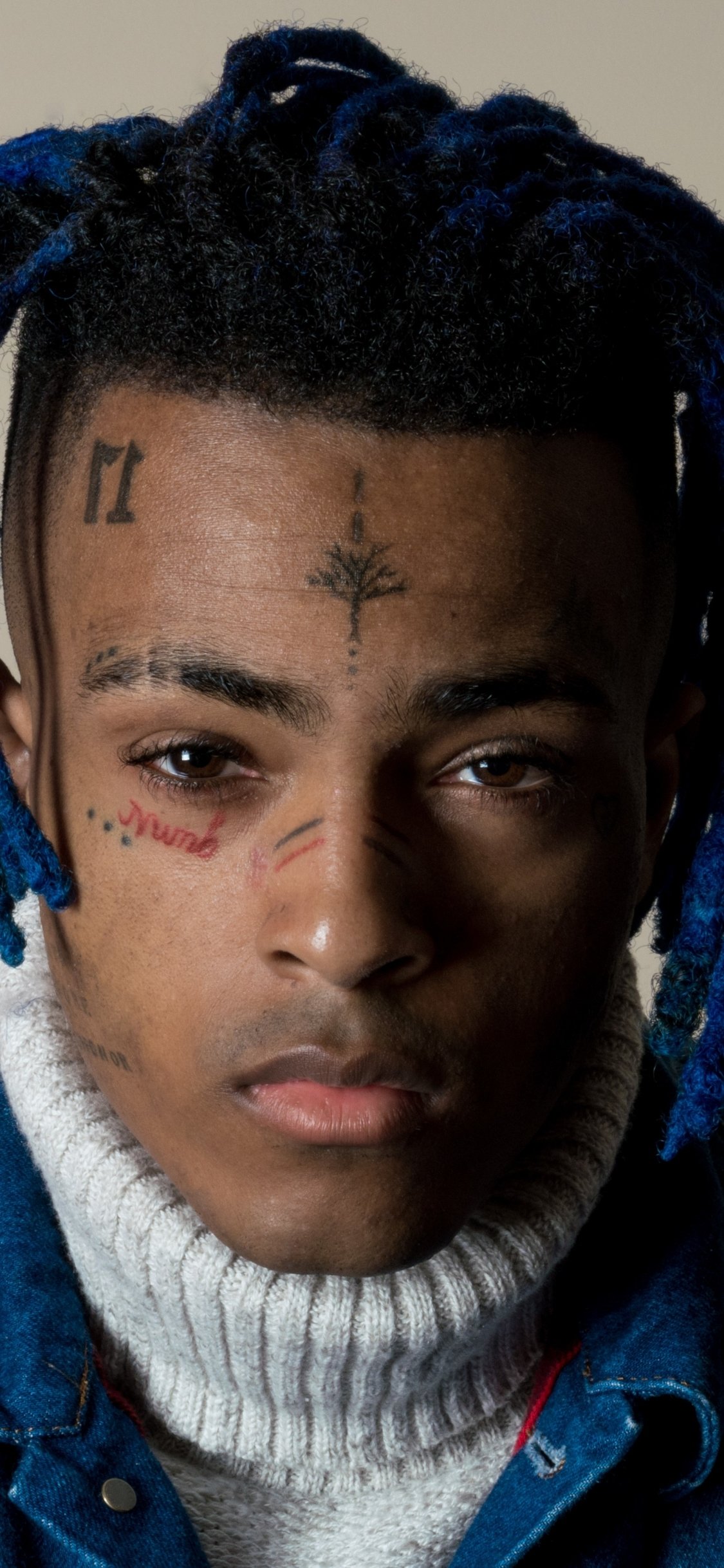 Phone wallpaper featuring a close-up portrait of rapper XXXTentacion with distinct facial tattoos, designed for both iPhone and Android screens.