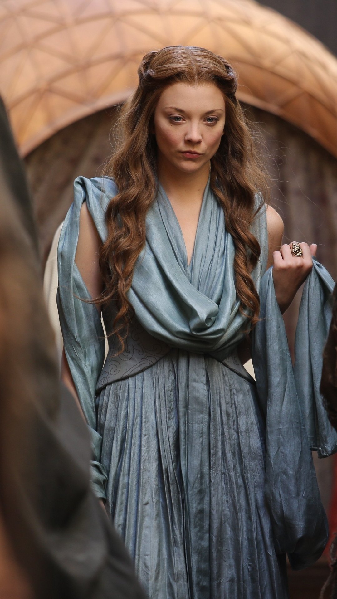Regal woman in a flowing blue medieval gown with braided hair, posed as a noble from a fantasy TV series — vertical phone wallpaper.