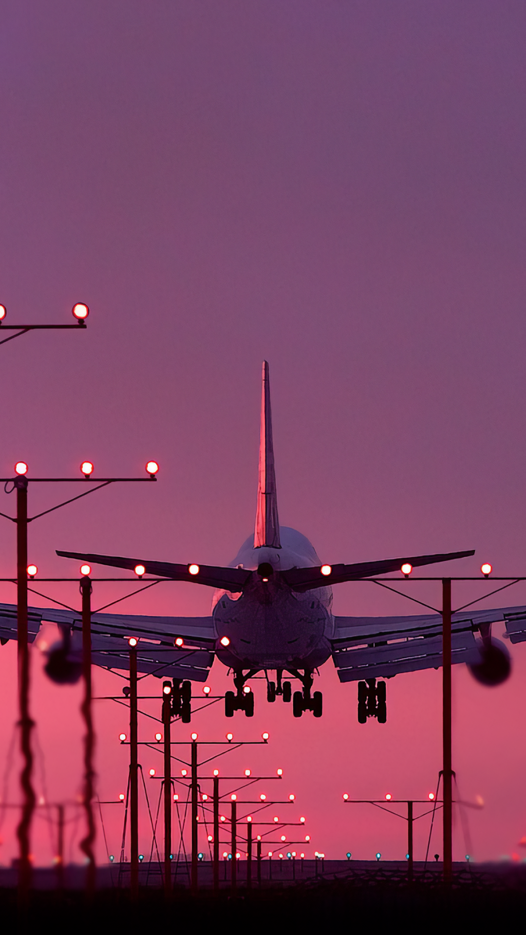 Phone wallpaper featuring a close-up of an airplane landing against a vibrant purple and pink sky, designed for both iPhone and Android screens.