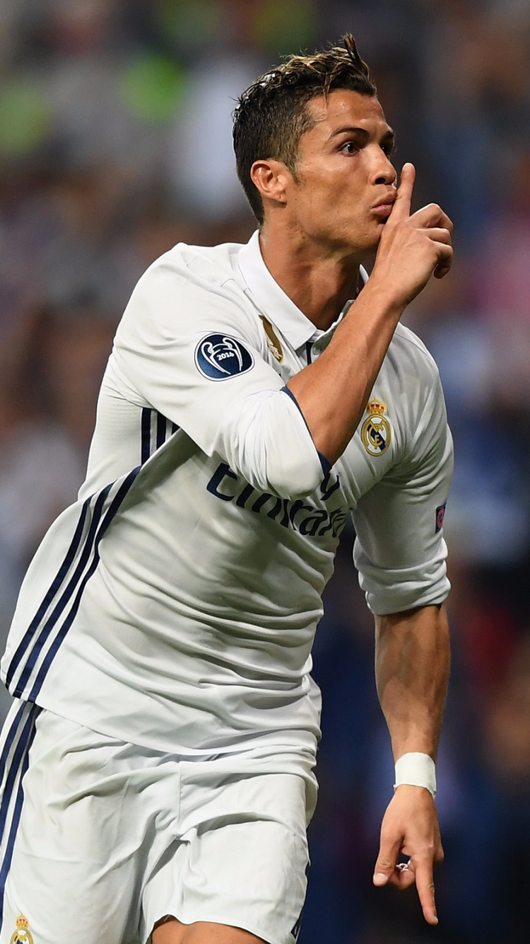 Phone wallpaper of a Portuguese soccer player in a white kit celebrating on the pitch, shushing the crowd — dynamic sports action portrait.