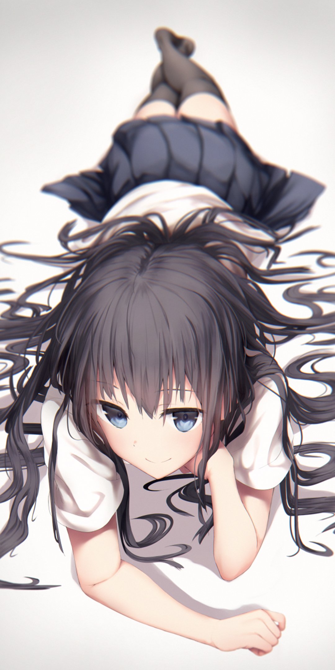 Phone wallpaper of an anime girl lying on her stomach, long dark hair fanned out, blue eyes, wearing a school uniform skirt and knee-high socks.