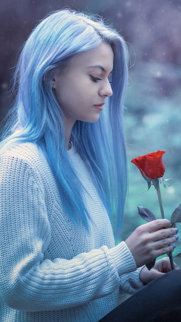 Phone wallpaper of a fantasy scene: a serene young woman with long blue hair holding a single red rose against a soft, misty background.