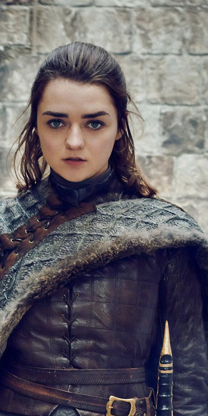 Phone wallpaper: young woman in Game of Thrones–style leather armor and fur cloak, fierce stare, braided hair and a sword at her side.