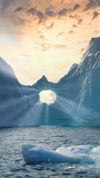  Sun rays shining through a hole in an iceberg