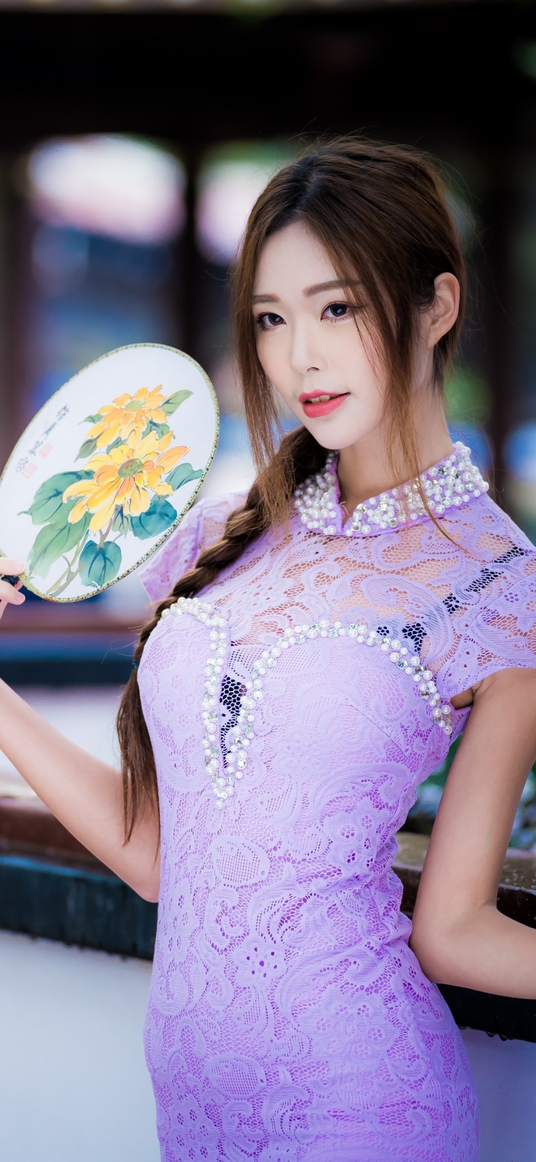 Brunette woman model in a purple lace dress, brown eyes, braided hair, holding a floral fan—elegant phone wallpaper