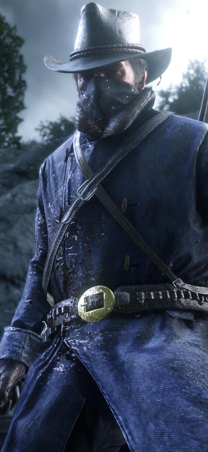Video game Red Dead Redemption 2 phone wallpaper: masked gunslinger in a wet coat and wide-brim hat, belt buckle gleaming against a moody, foggy outdoor backdrop.