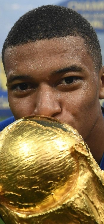 Phone wallpaper: close-up of a French soccer player kissing the golden World Cup trophy in a celebratory sports portrait.