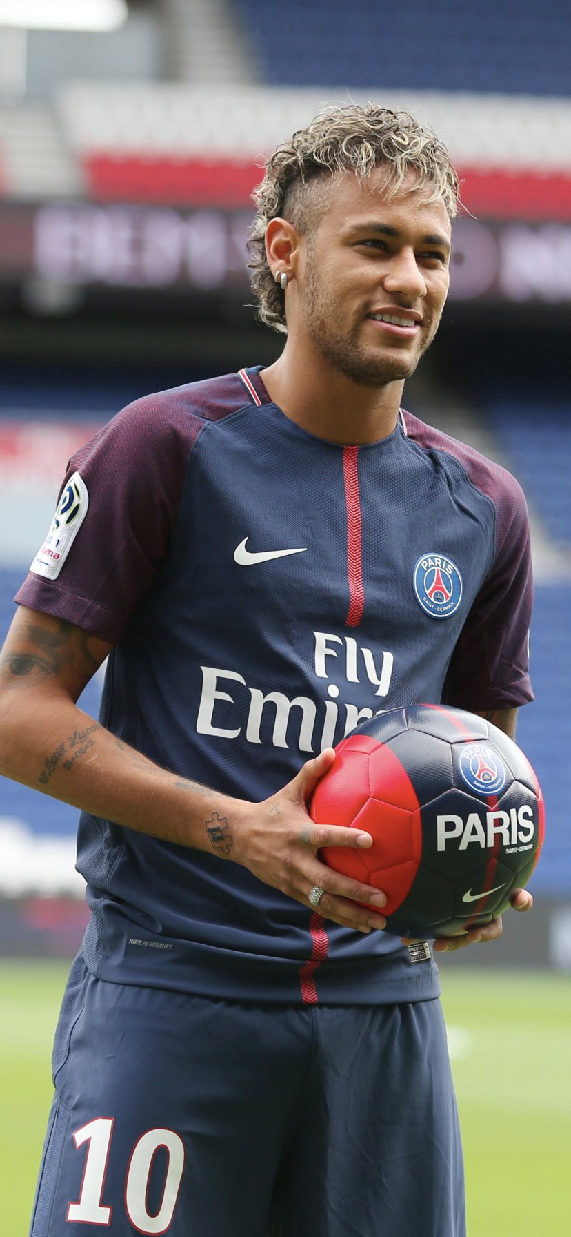 Phone wallpaper featuring Brazilian soccer star Neymar in Paris Saint-Germain kit, holding a ball, blending sports energy and vibrant team colors for iPhone and Android.