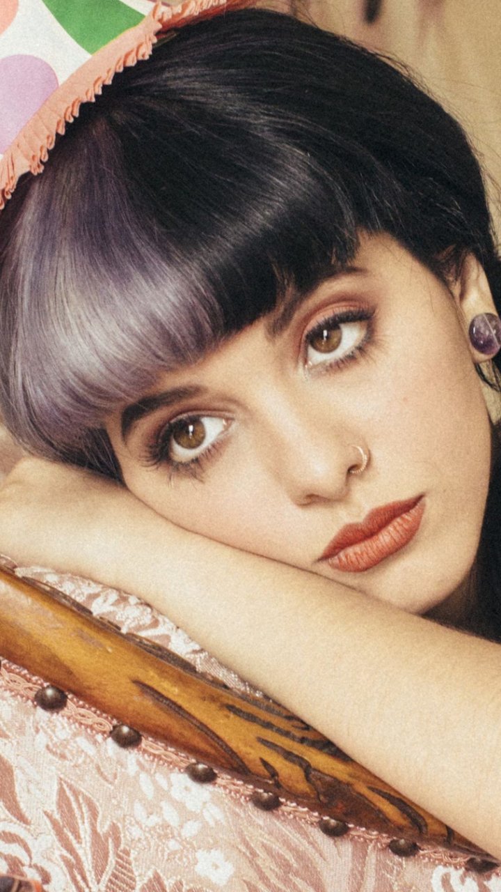 Phone wallpaper featuring American singer Melanie Martinez with her signature two-tone hair and distinct makeup, designed for both iPhone and Android displays.