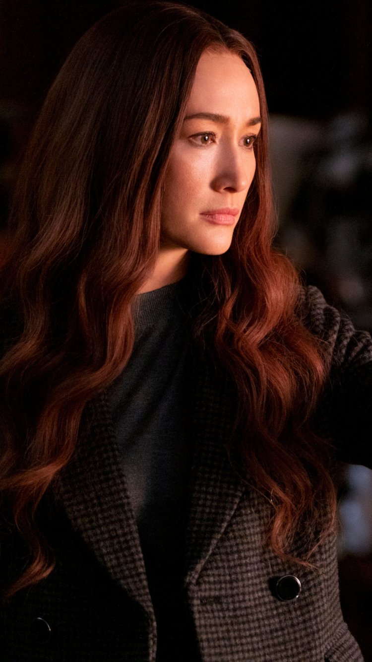Phone wallpaper featuring Maggie Q from the movie The Protégé, with warm lighting and a thoughtful expression, optimized for iPhone and Android displays.