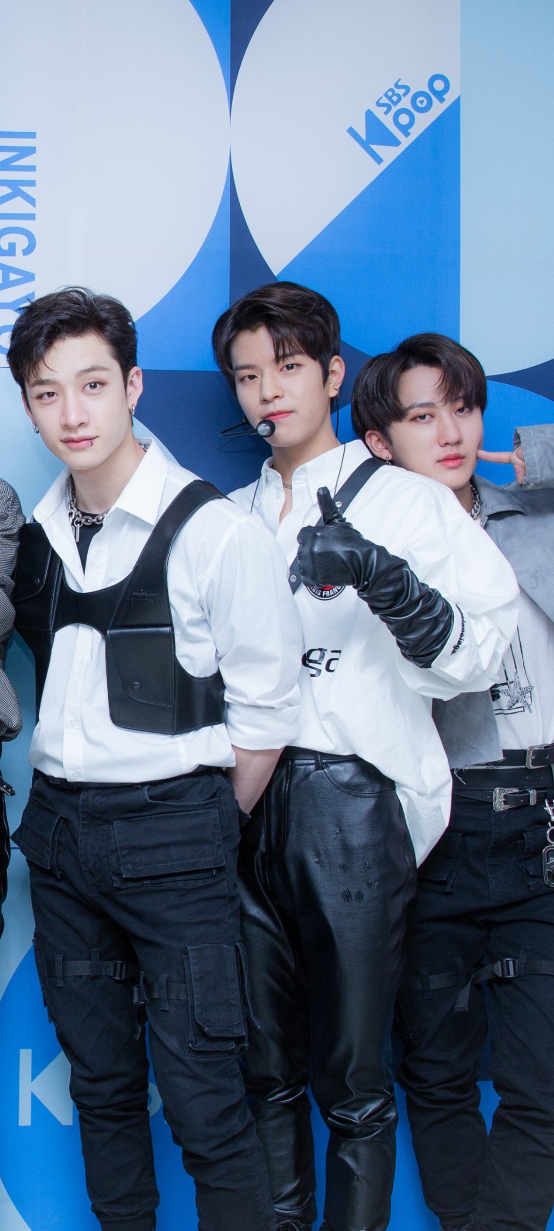Phone wallpaper for iPhone and Android: three K-pop boy band members in coordinated black-and-white outfits posing against a blue, music-themed backdrop.