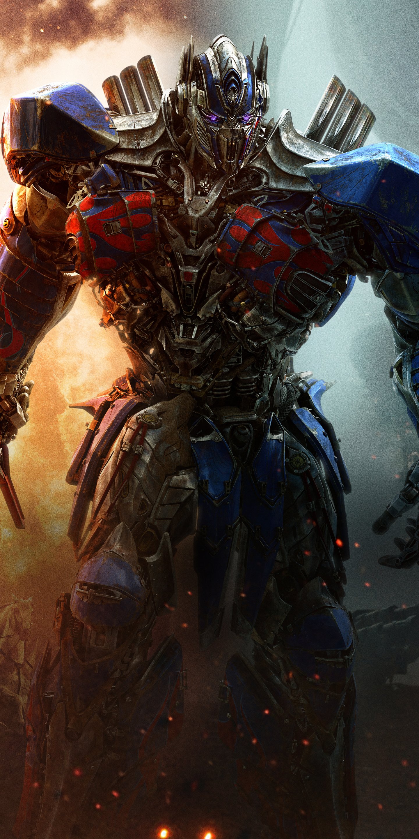 Phone wallpaper of Optimus Prime from the movie Transformers: The Last Knight — red-and-blue Autobot in battle-worn armor standing amid fire and smoke.