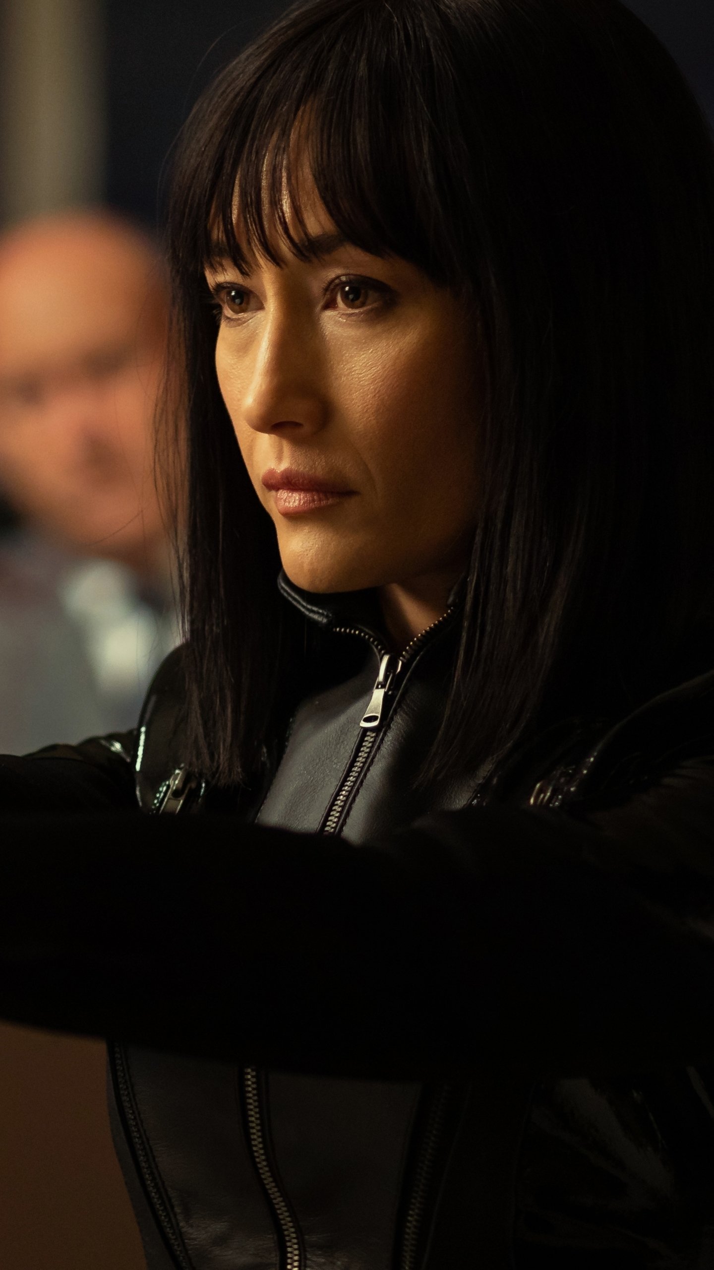 Phone wallpaper featuring Maggie Q from the movie The Protégé, designed for both iPhone and Android screens.