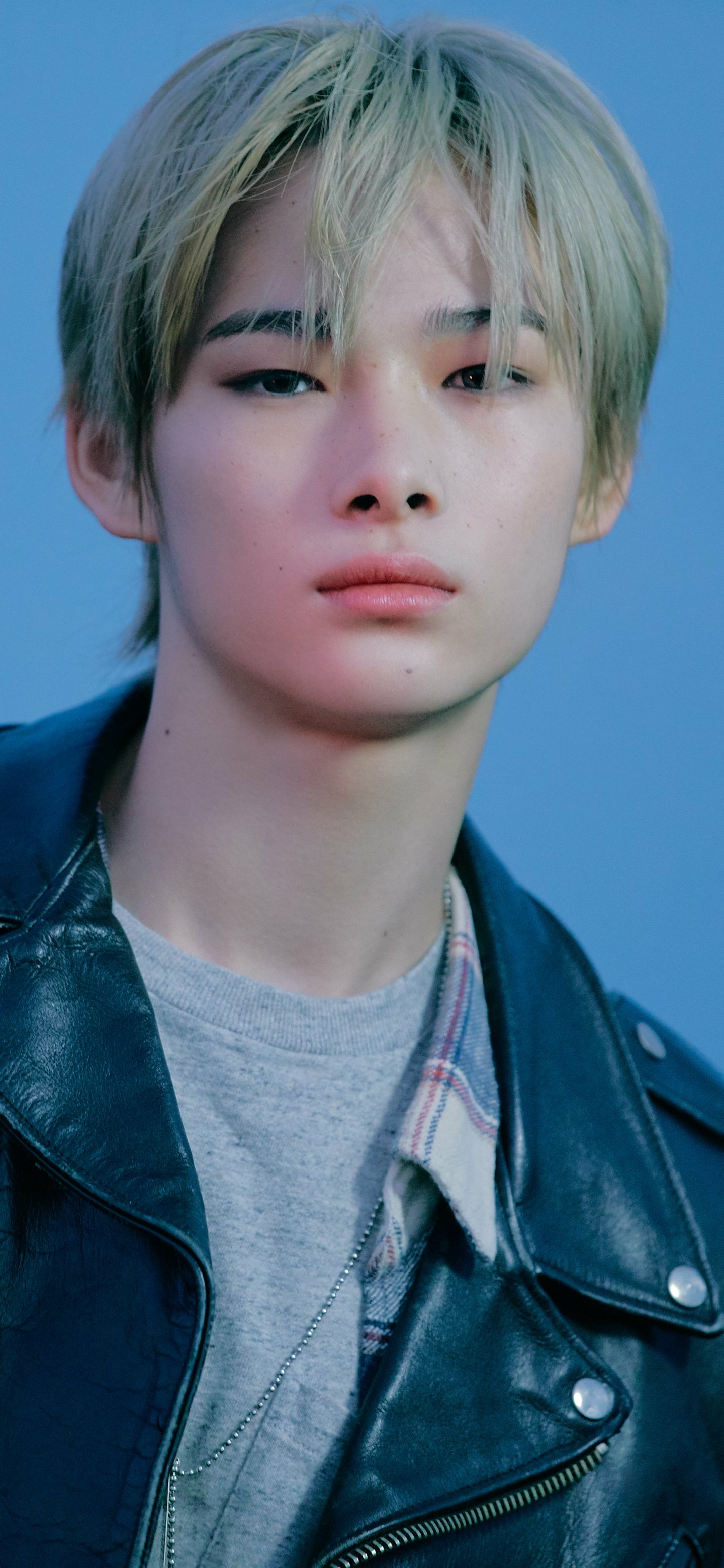 Close-up phone wallpaper of a young person against a soft blue background, music-themed and tagged ENHYPEN.