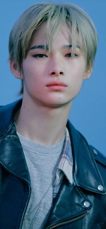 Close-up phone wallpaper of a young person against a soft blue background, music-themed and tagged ENHYPEN.