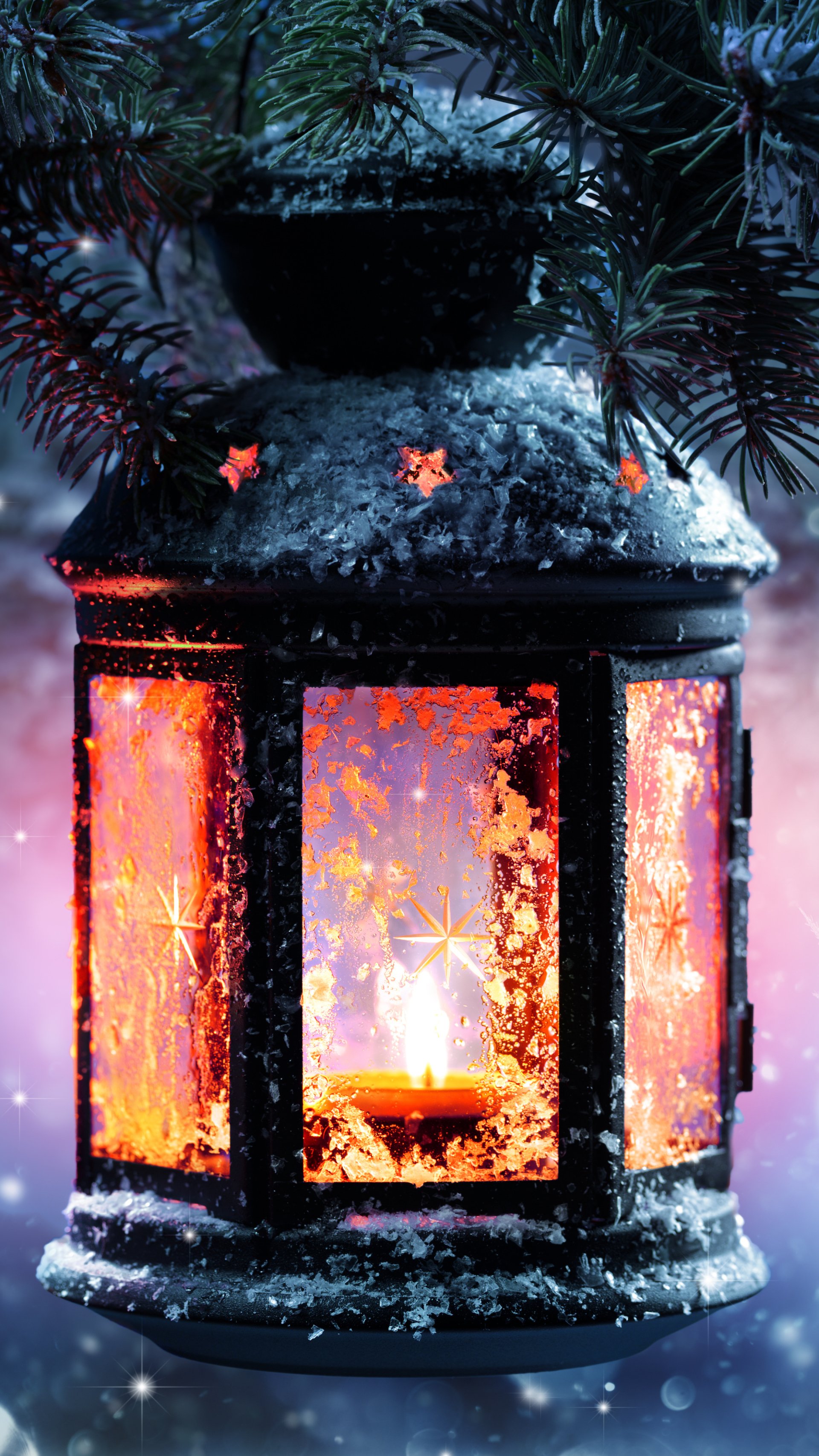 Christmas holiday phone wallpaper: glowing lantern dusted with snow beneath evergreen branches, warm candlelight and frosty star patterns against a dusky blue sky.