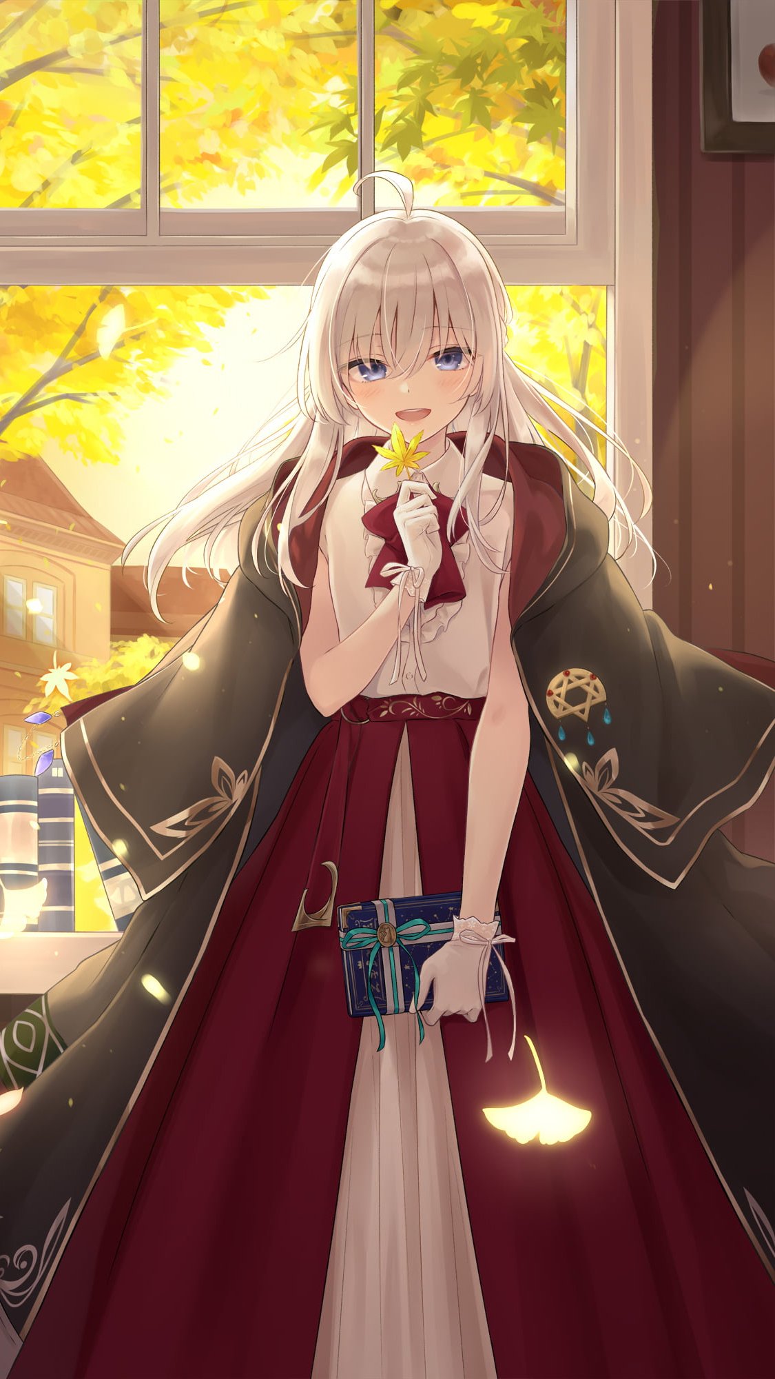 Phone wallpaper of Elaina from Wandering Witch: The Journey of Elaina — blonde witch in a burgundy dress and embroidered cloak by a sunlit window, holding a book and a glowing yellow leaf.
