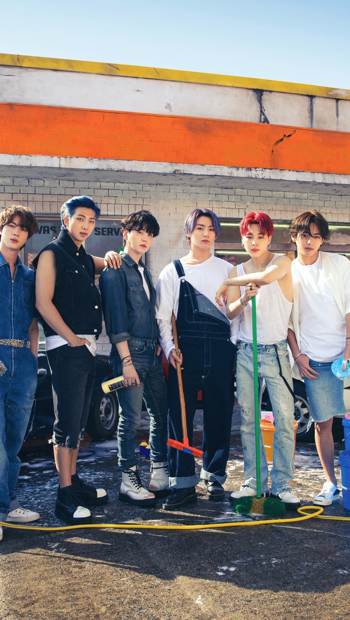 Phone wallpaper featuring BTS members standing outdoors with casual outfits, designed for both iPhone and Android users, capturing the energy of music and the group’s style.