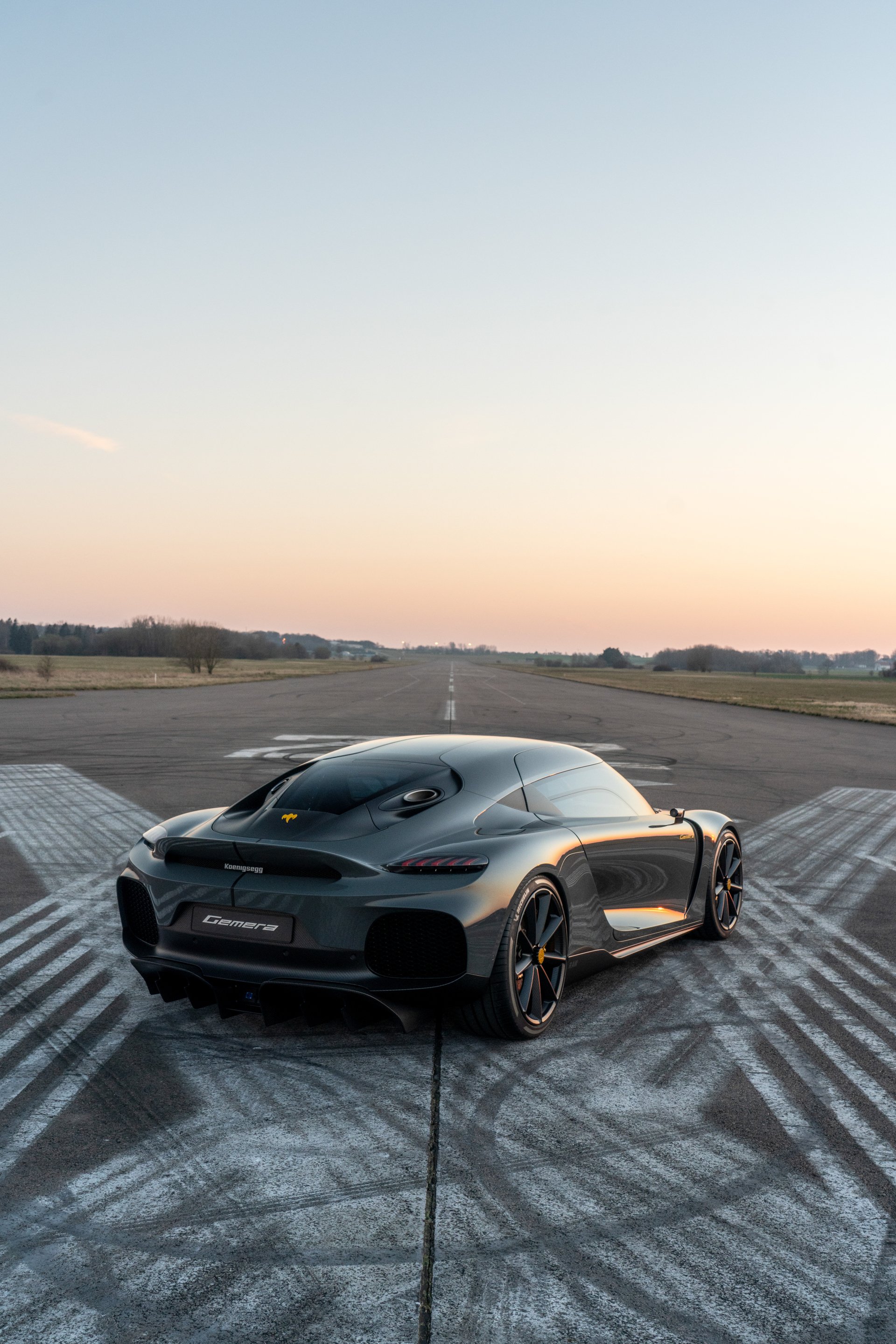 A sleek Koenigsegg Gemera parked on a runway, capturing the essence of luxury performance. This stunning image makes an eye-catching phone wallpaper.