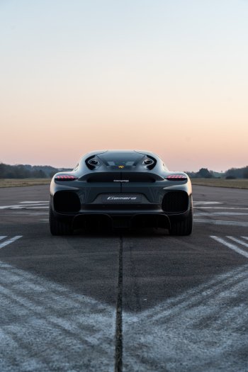 A sleek Koenigsegg Gemera stands on a runway against a serene sunset, offering a striking look for a phone wallpaper.